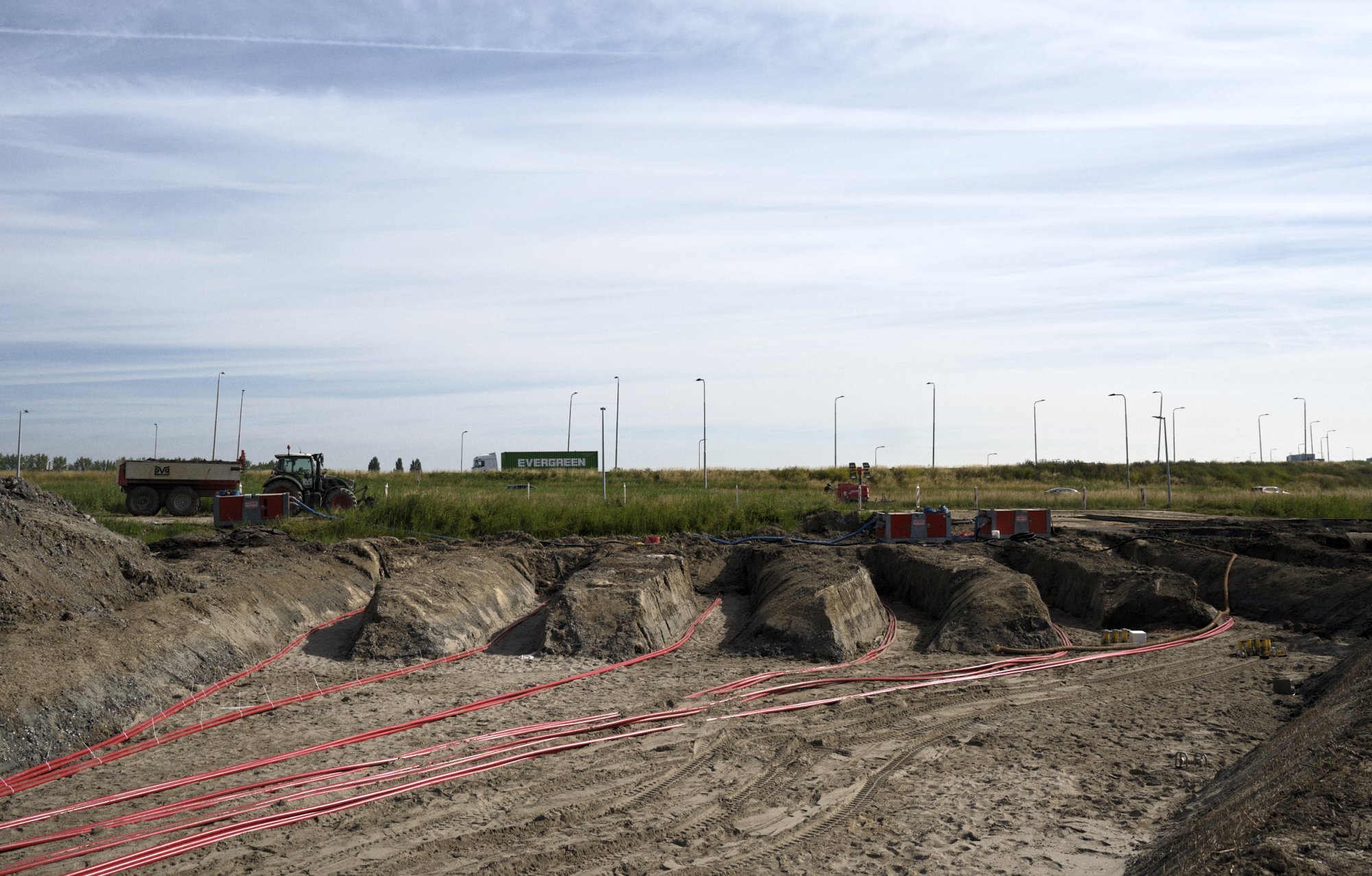 Gegraven sleuven met rode elektriciteitskabels voor netaansluiting.