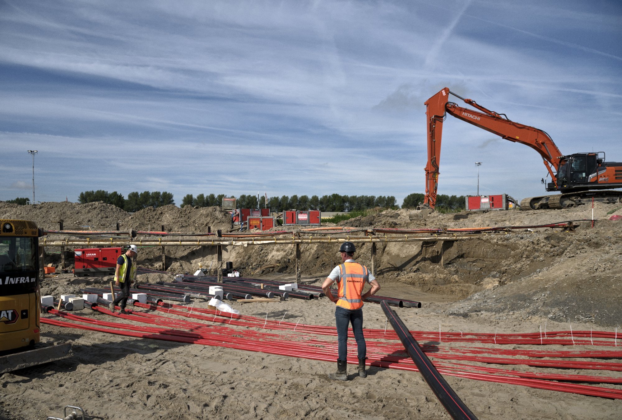 Rode elektriciteitskabels liggen in een sleuf klaar voor aansluiting.